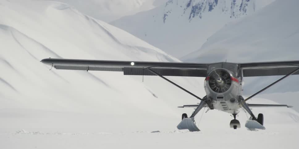 A small ski plane lands in the snow
