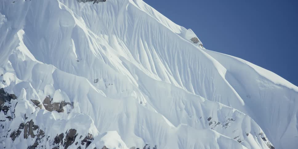 A mountain covered with snow with the sky in the background