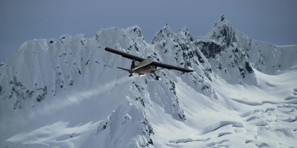 An airplane flies past a mountain range during the winter