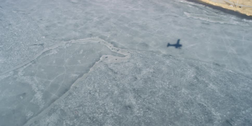 The shadow of a flying light aircraft on ice