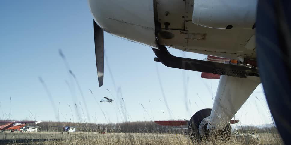 Planes sit in an airfield as another aircraft takes off