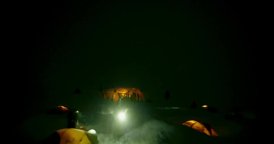 Dramatic aerial pulling away from people and tents in snowy camp