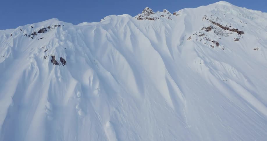 Aerial pulling away from an impressive snowy mountain