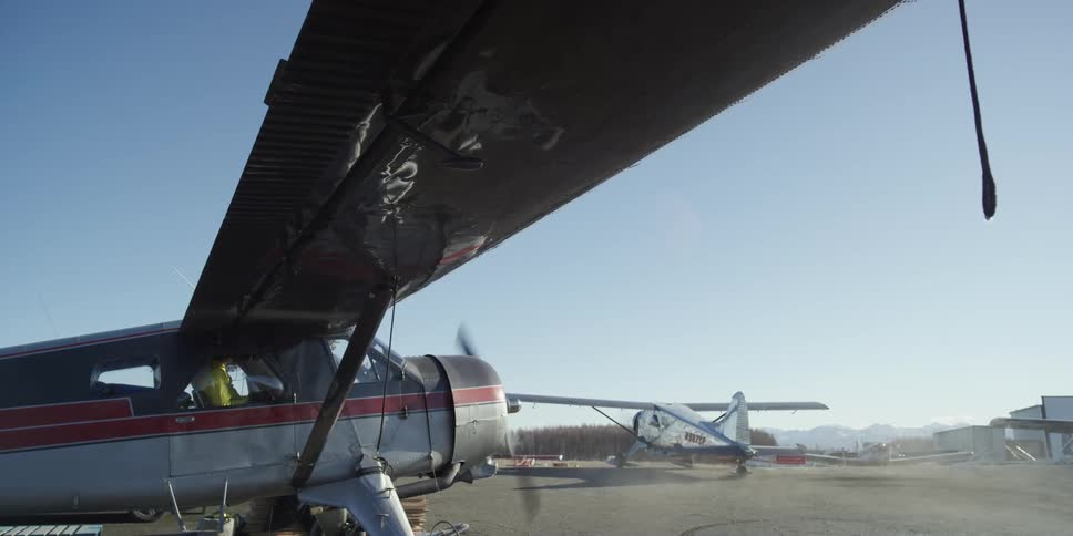 Blades spinning on a grounded aircraft at a small airfield