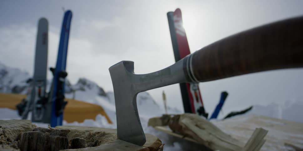 An ax and skis at a camping spot in the mountains