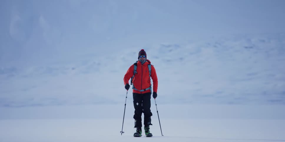 A man with skis walking on snow and ice