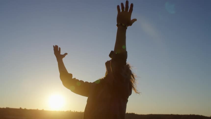 A man stands outside with his arms raised up in the air