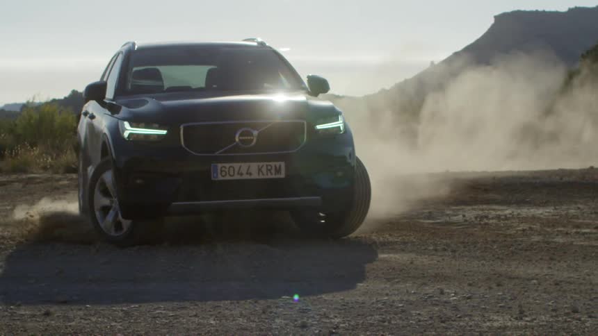 A vehicle kicking up dust behind it as it makes a sharp turn in dirt