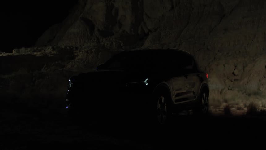 A spotlight passes over an suv parked off road in the desert flashing its lights
