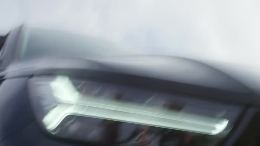 A sports car races quickly down a road near mountains