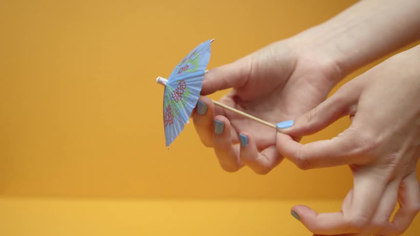 A person opens and closes a drink umbrella