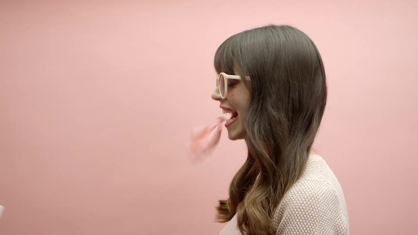 A woman blows a bubble and another woman pops it