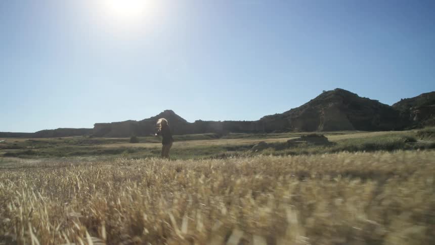 A man holding a stick dances while standing in a grassy area