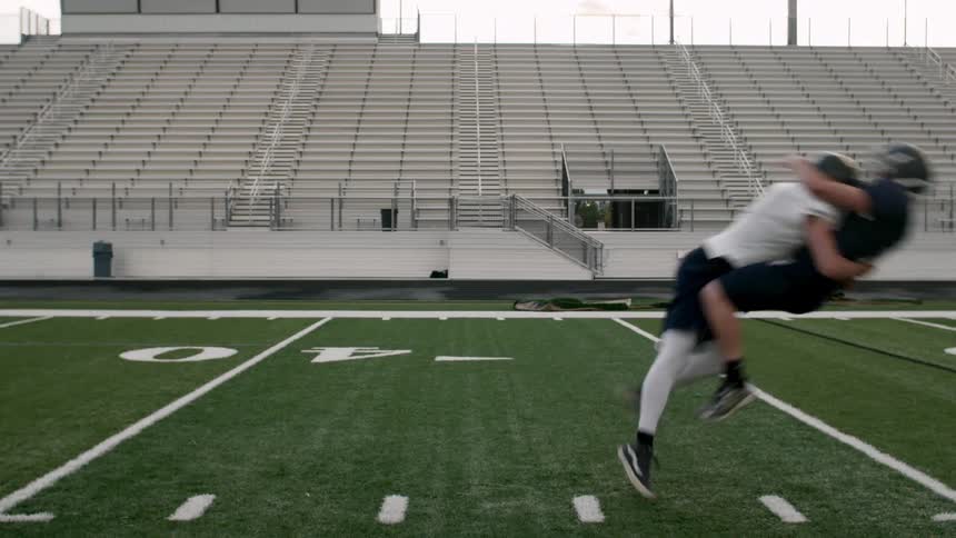 A receiver catches a football and is tackled