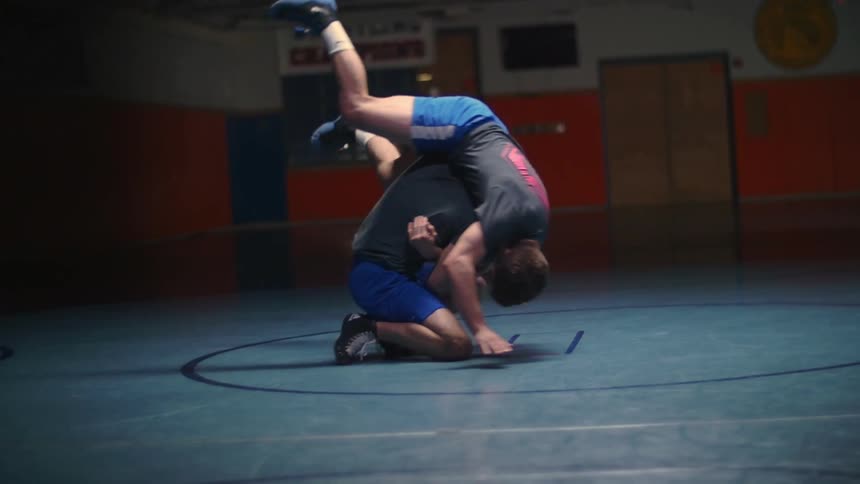 Two people are wrestling in a gym
