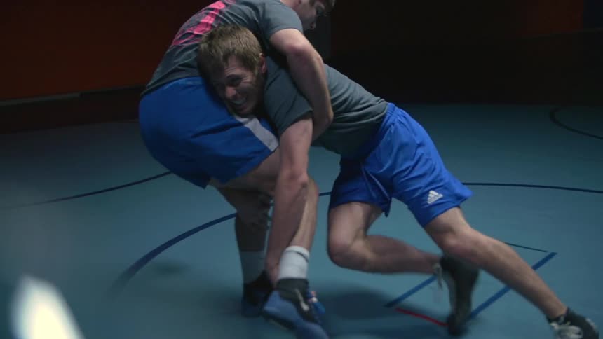 Two men are wrestling in a gym together