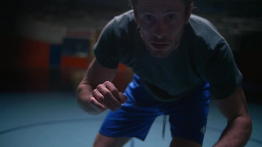A man is preparing to wrestle in a gym