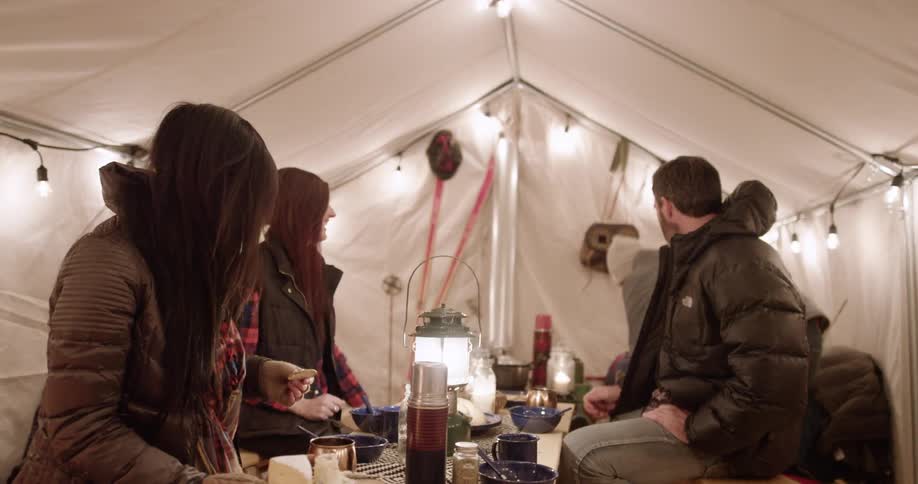 A group of people eat around a table in a tent