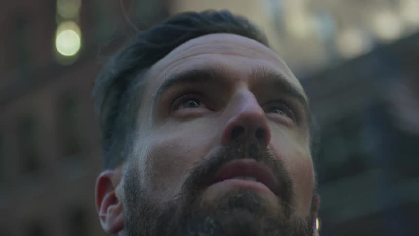 A man is standing in front of some buildings looking up