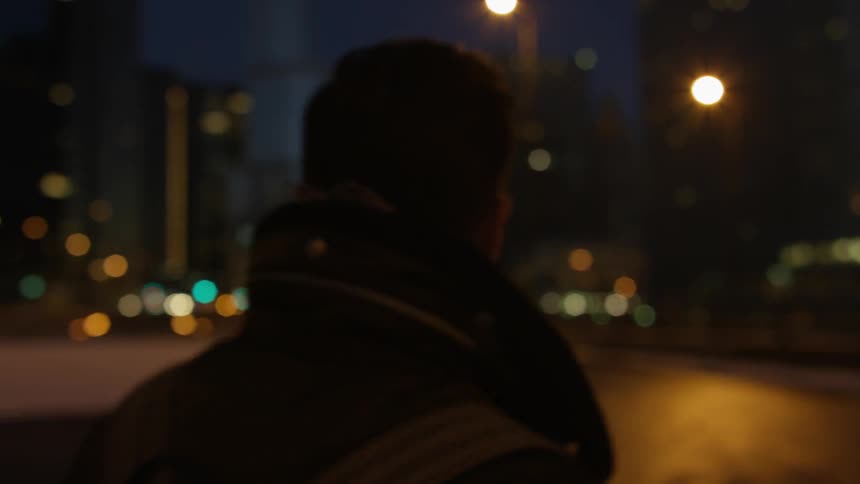 A person is walking quickly in a city on a cold night