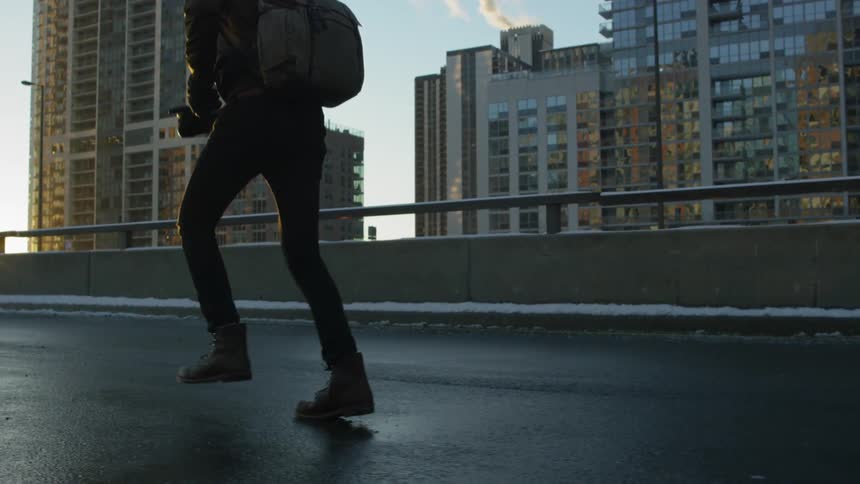 A man runs down a city street with skyscrapers in the background