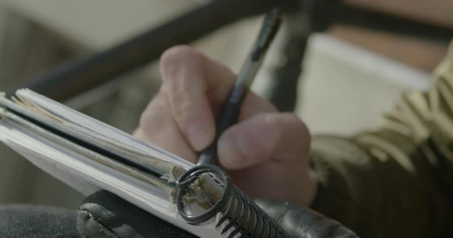A person is writing with a pen in a notebook