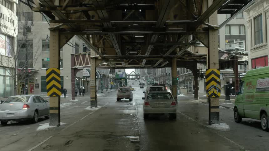 Cars travel under a train underpass in city traffic