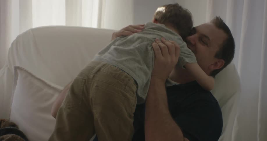 A man lifts a boy above his head and hugs him