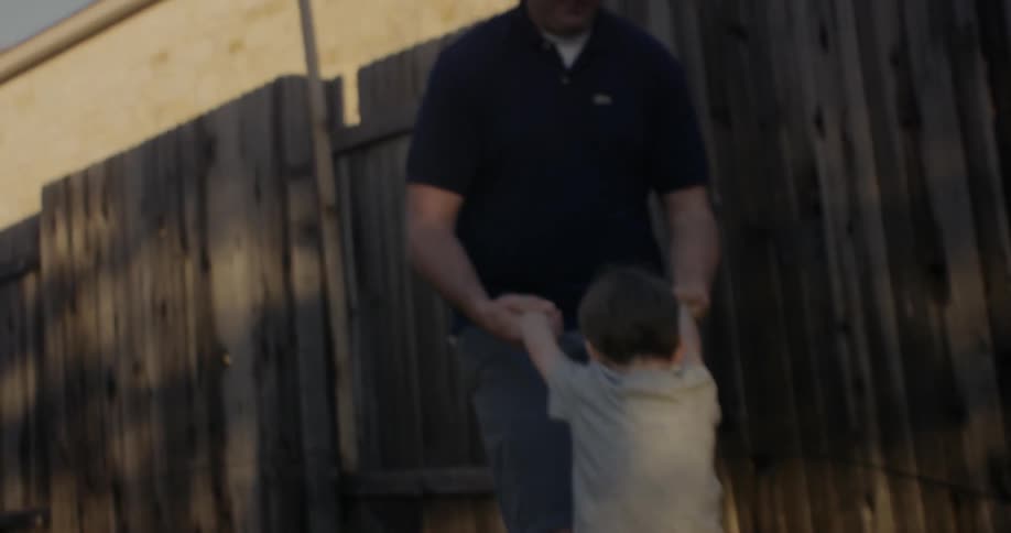 A boy runs to a man and does a flip
