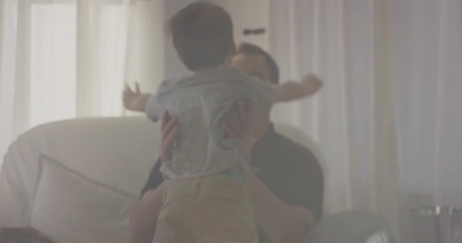 A boy runs into a house over to a man's arms