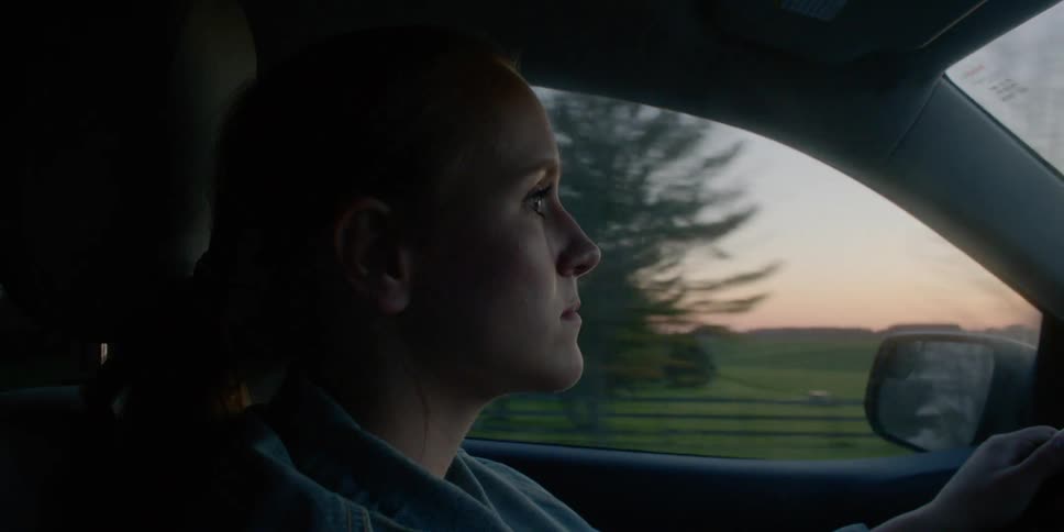 A woman is driving near a field