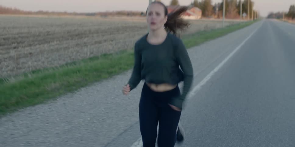 A white woman runs down a rural road