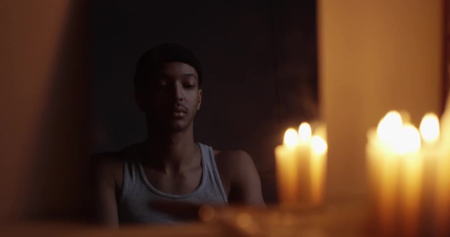 A man looking into a mirror with candles burning