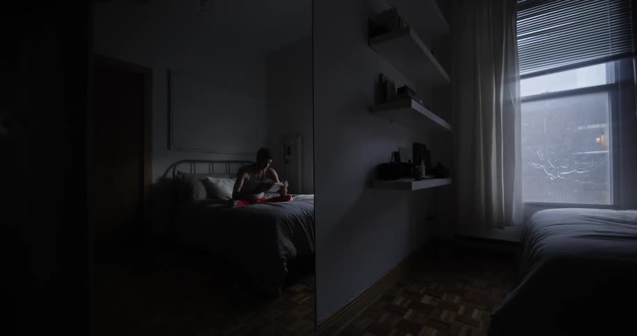 A teenager sits on a bed and reads