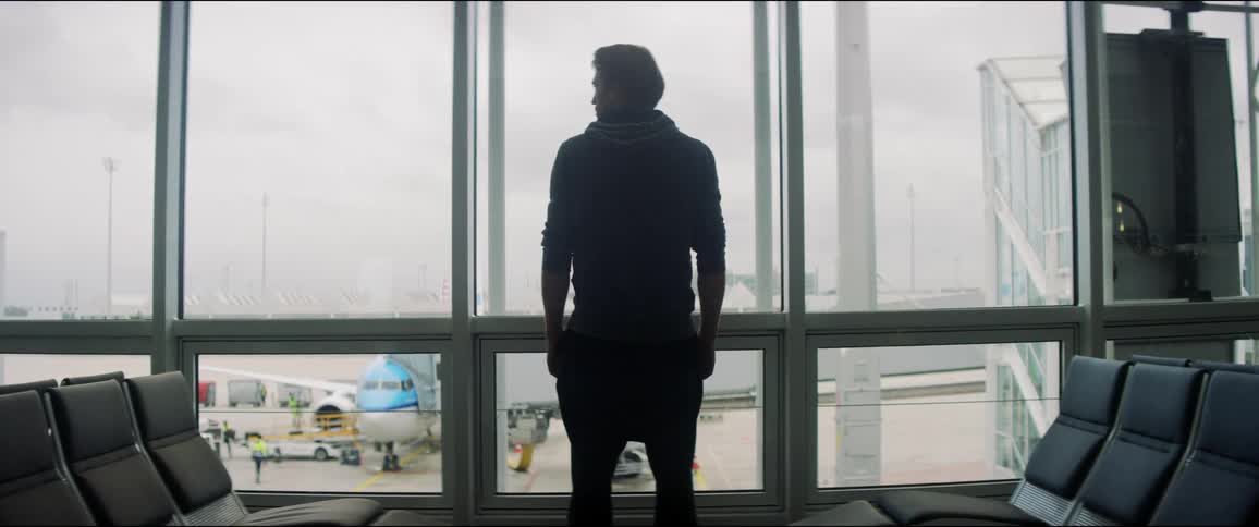 A man standing by the window in an airport