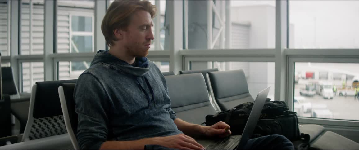 A man using a laptop while sitting in the waiting area of an airport