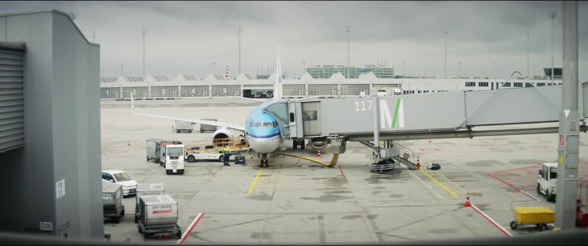 A plane sits at an airport with a jet bridge attached to it