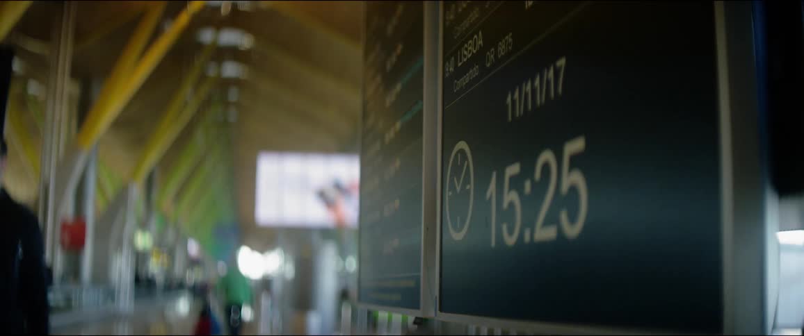Departure times at an airport are shown changing as people walk past