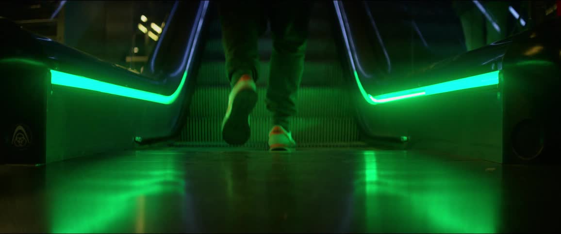 A person walks up an elevator illuminated by green lighting