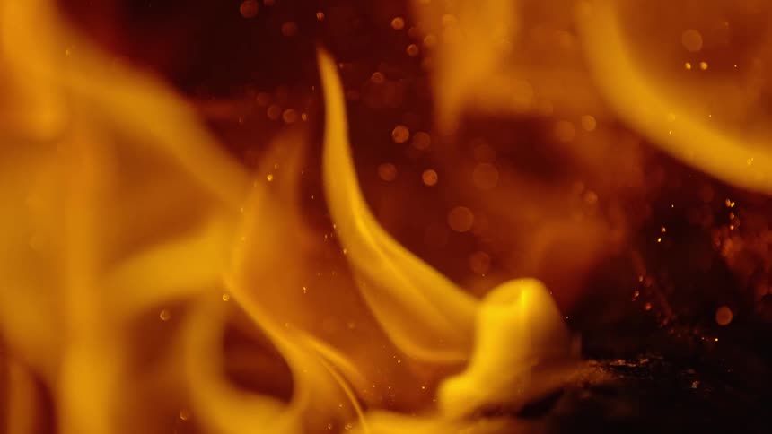 Embers and sparks fly up as a fire burns