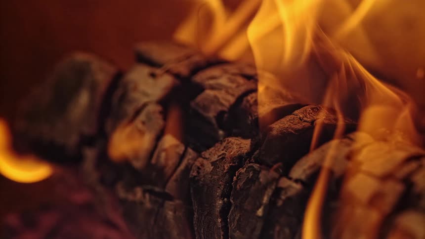 Yellow orange flames dance over charred wood