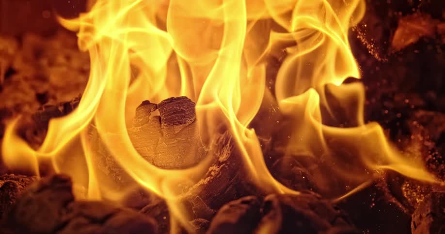 A wood burning fire sparks and pops as it flames bright yellow