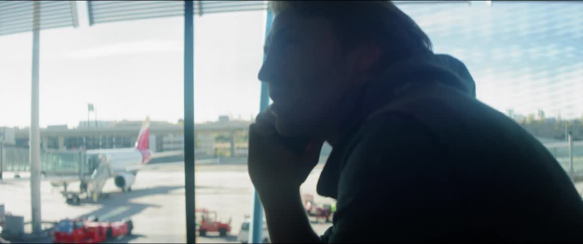 Silhouette of man talking on cell phone while waiting for his flight at airport