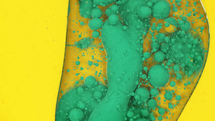 Green lumps flow through clear liquid surrounded by yellow