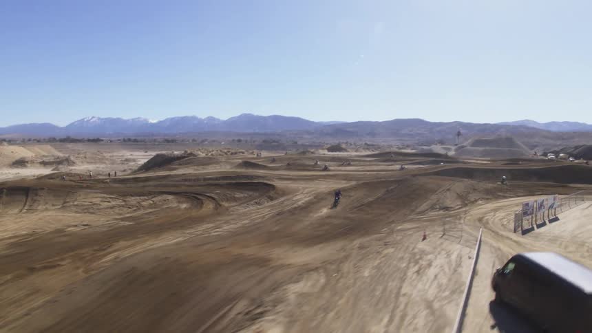 Racers race on a large dirt bike track