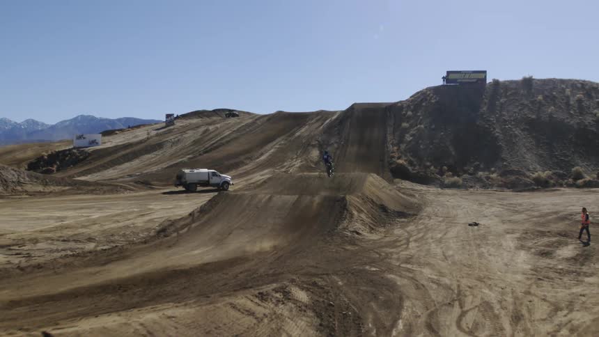 A motorcycle jumps an obstacle on a dirt track