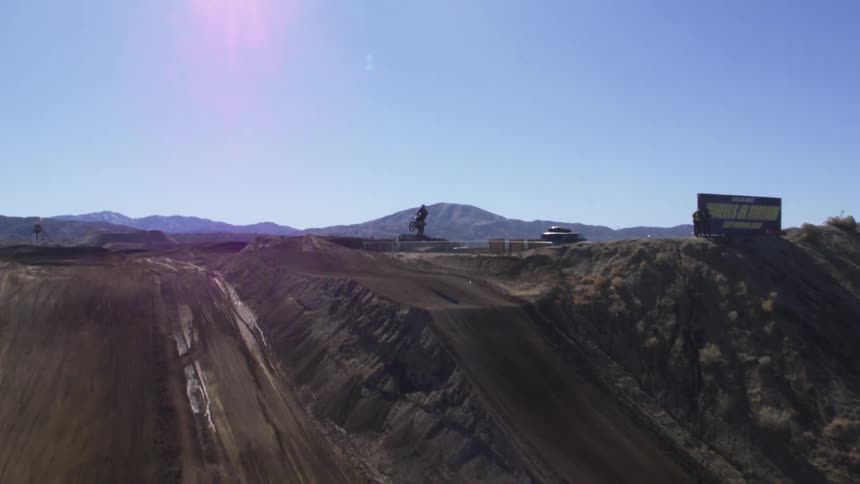 A motorcyclist rides up a dirt ramp and makes a jump
