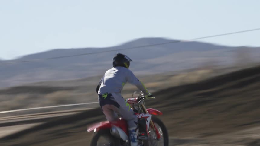 A motocross rider jumps over a dirt hill