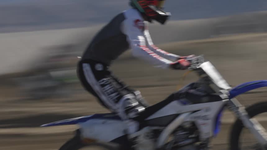 A person rides a dirt bike on a dirt track