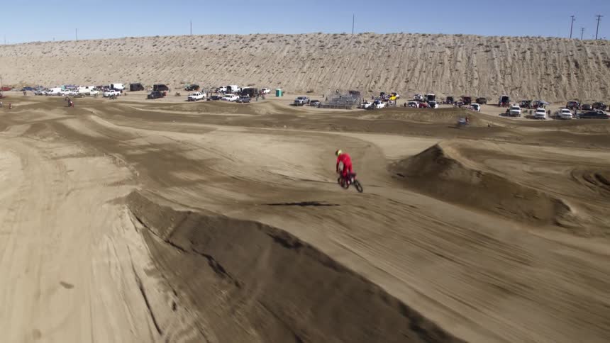 Bike riders ride on a motocross area and jump over the dunes
